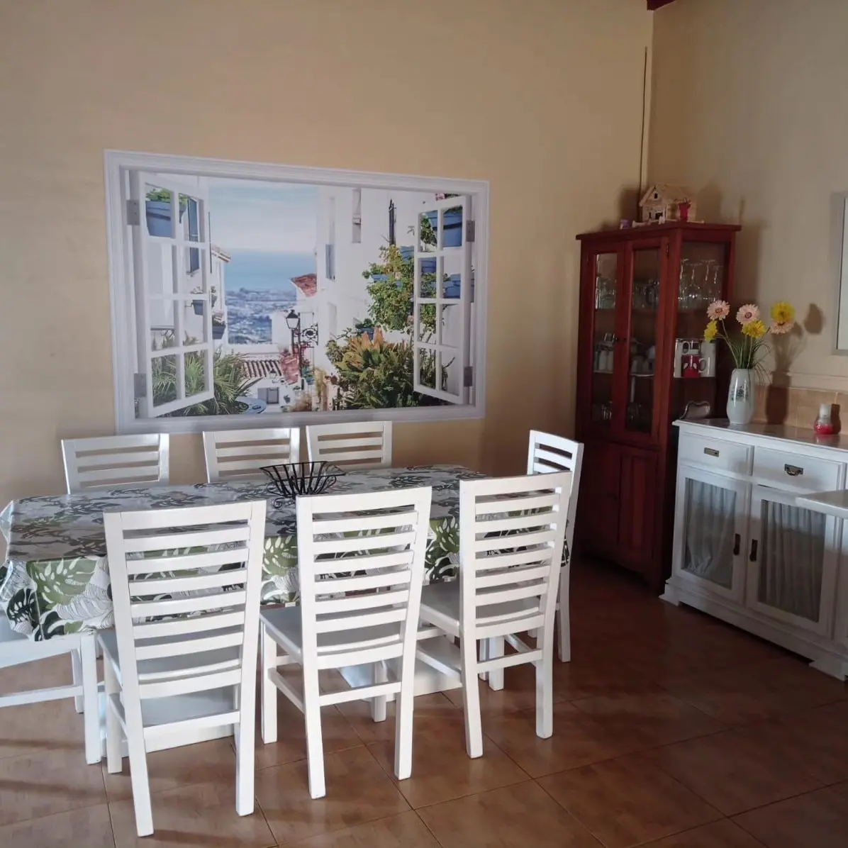 Comedor de Villa Meli con un mural de ventana abierta con vistas al pueblo de Mijas