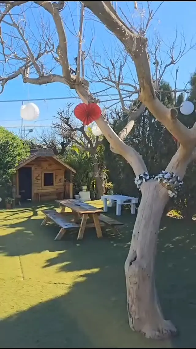 Jardín de Villa Meli con casita de madera infantil, mesa de pícnic y árbol decorado con farolillos