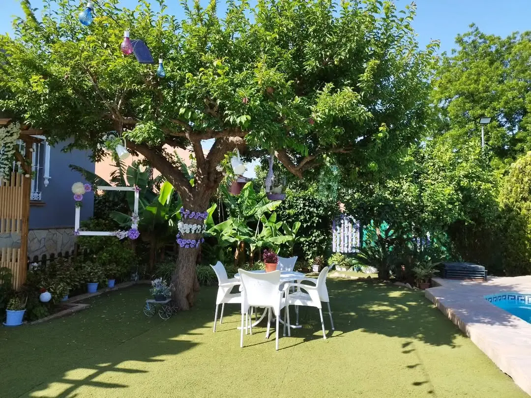 Mesa con sillas a la sombra de un gran árbol en el jardín de Villa Meli