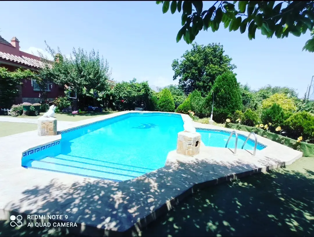 Piscina de Villa Meli con escalera romana y greca de azulejo, con la casa de ladrillo al fondo