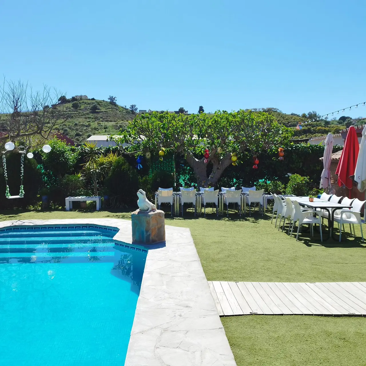 Piscina de Villa Meli con pasarela de madera y zona de mesas junto al césped